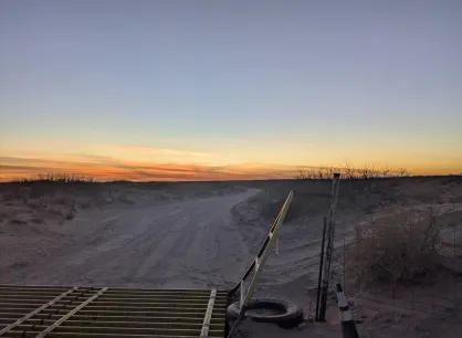 Sunset over desert with cattle gate and fence